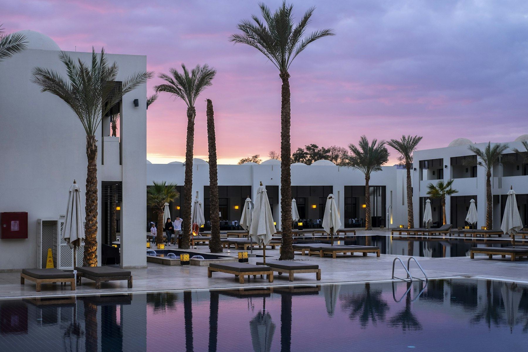 A resort pool and palm trees at sunset